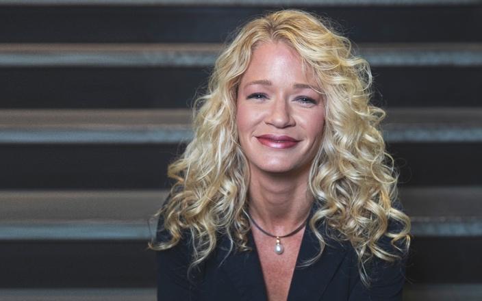 A person with blonde hair smiling Description automatically generated